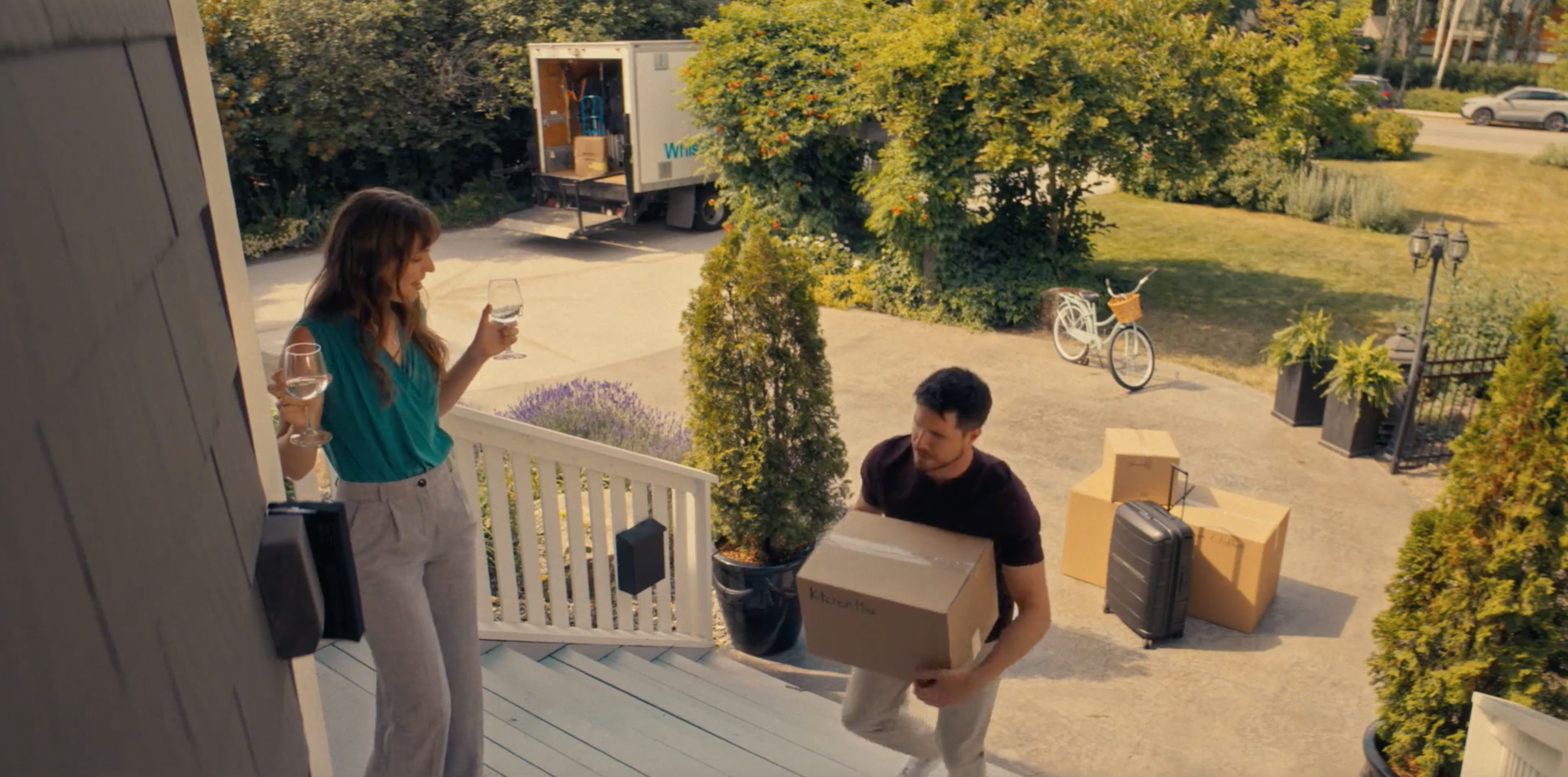 ali holds wine while graham carries boxes into house