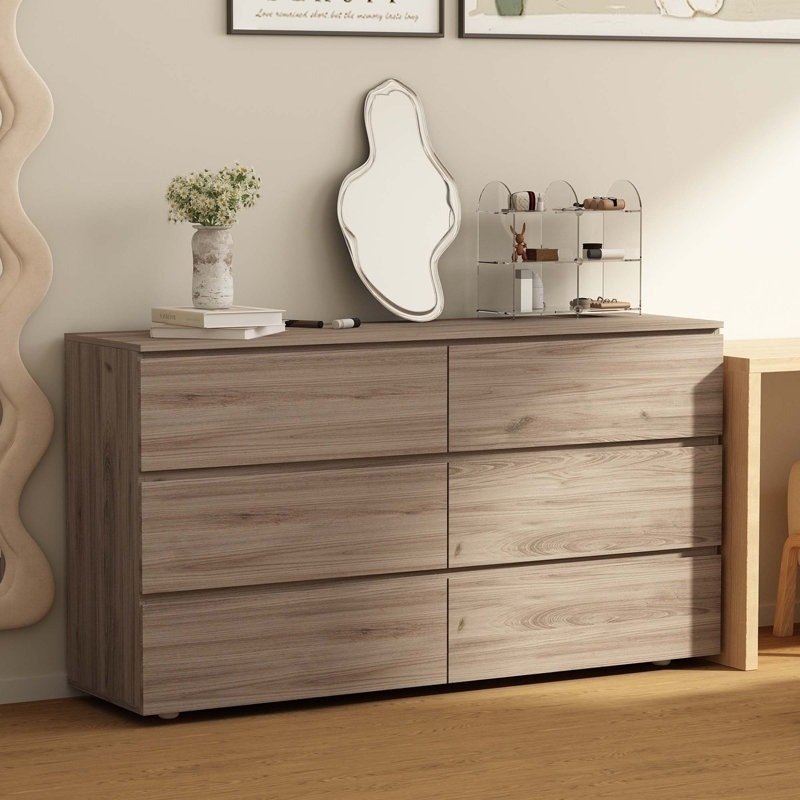 wood six-drawer dresser with beauty products and squiggle mirror on top