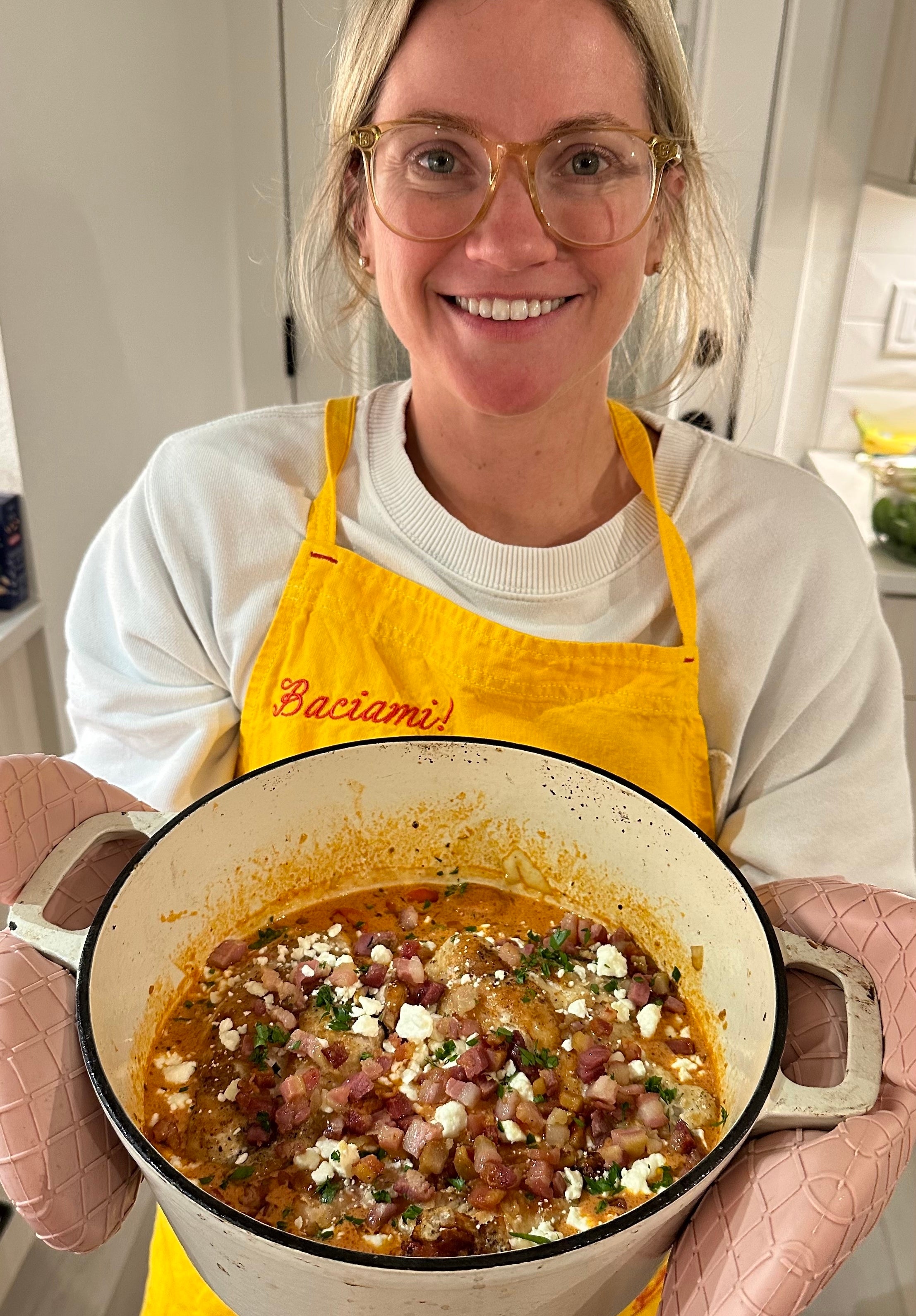 the author holding a dutch oven of creamy tomato chicken with feta
