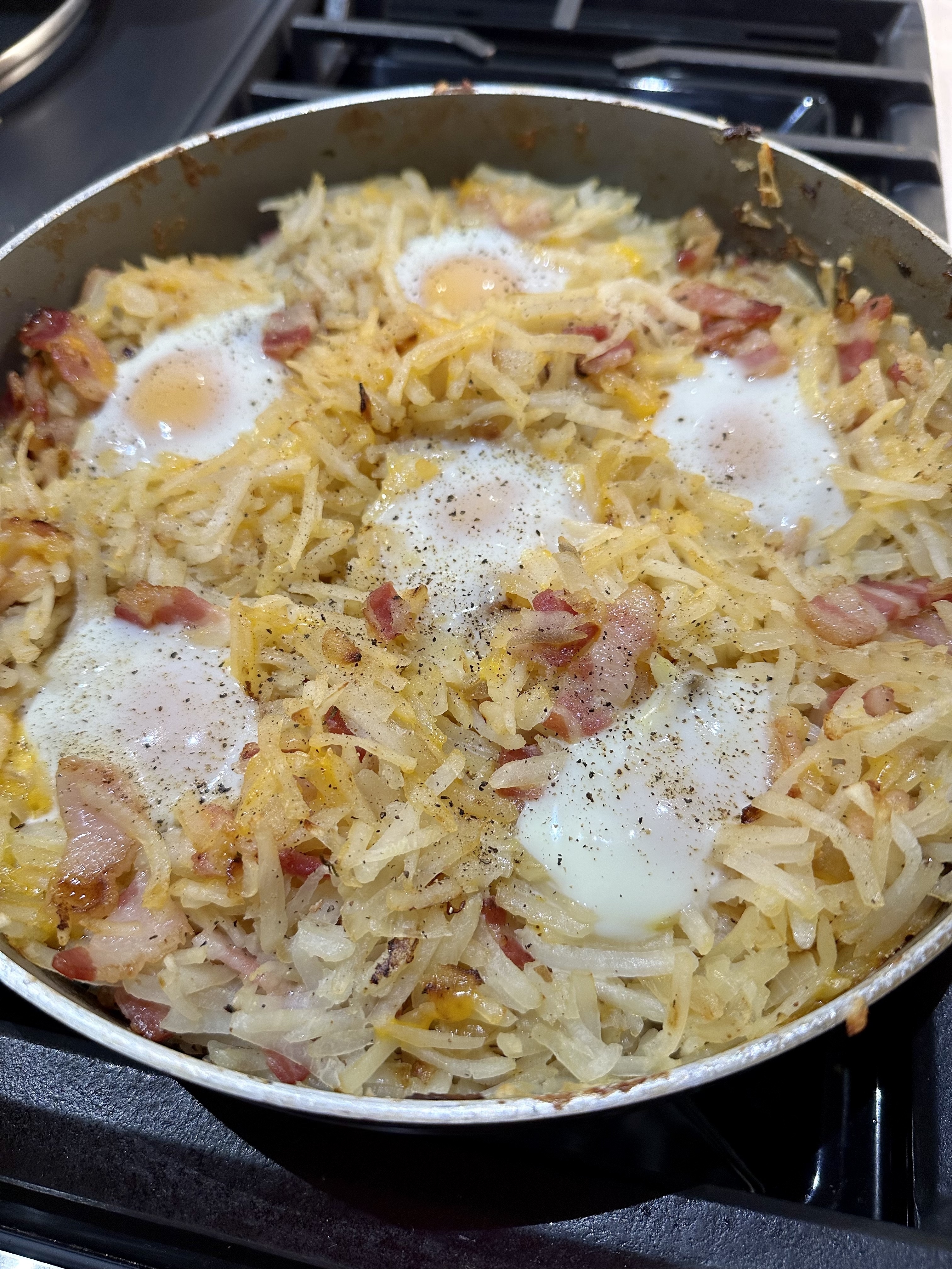 hashbrown, eggs, bacon, and cheese in a skillet