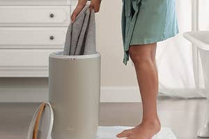 Person pulling towels out of upright towel warmer 