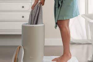Person pulling towels out of upright towel warmer 