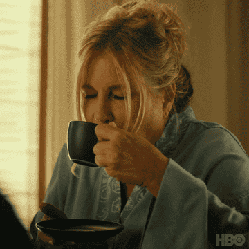 Jennifer Coolidge drinking out of a mug and smiling
