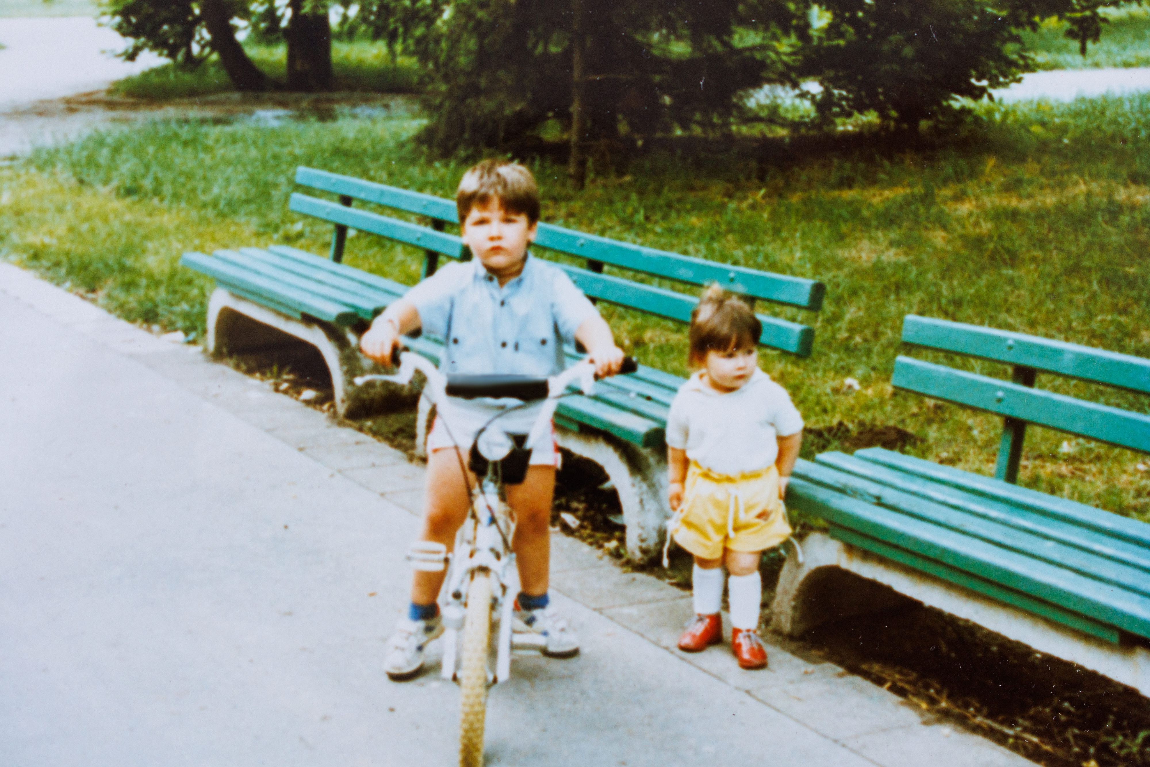two kids in a park with one on a bike