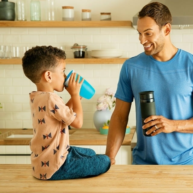 toddler using blue sippy cup to drink