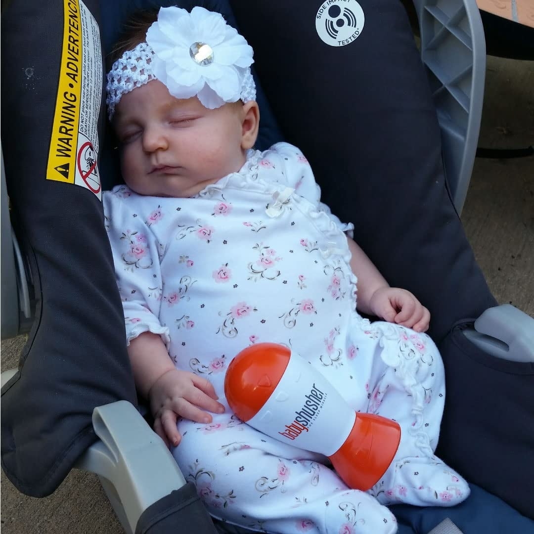 orange and white babyshusher next to sleeping baby in car seat