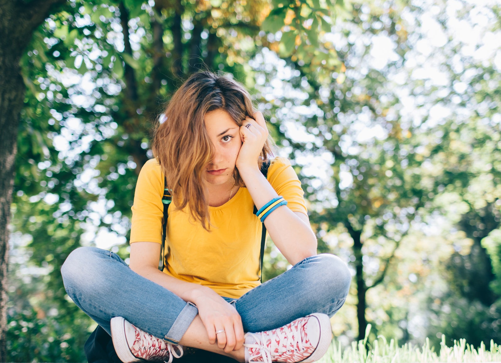 Upset angsty teen sitting cross-legged with hair in front of face