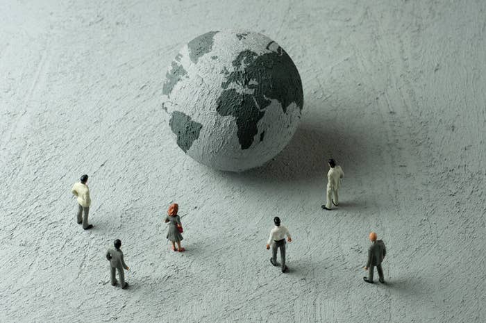 Mini people standing next to a mini Earth