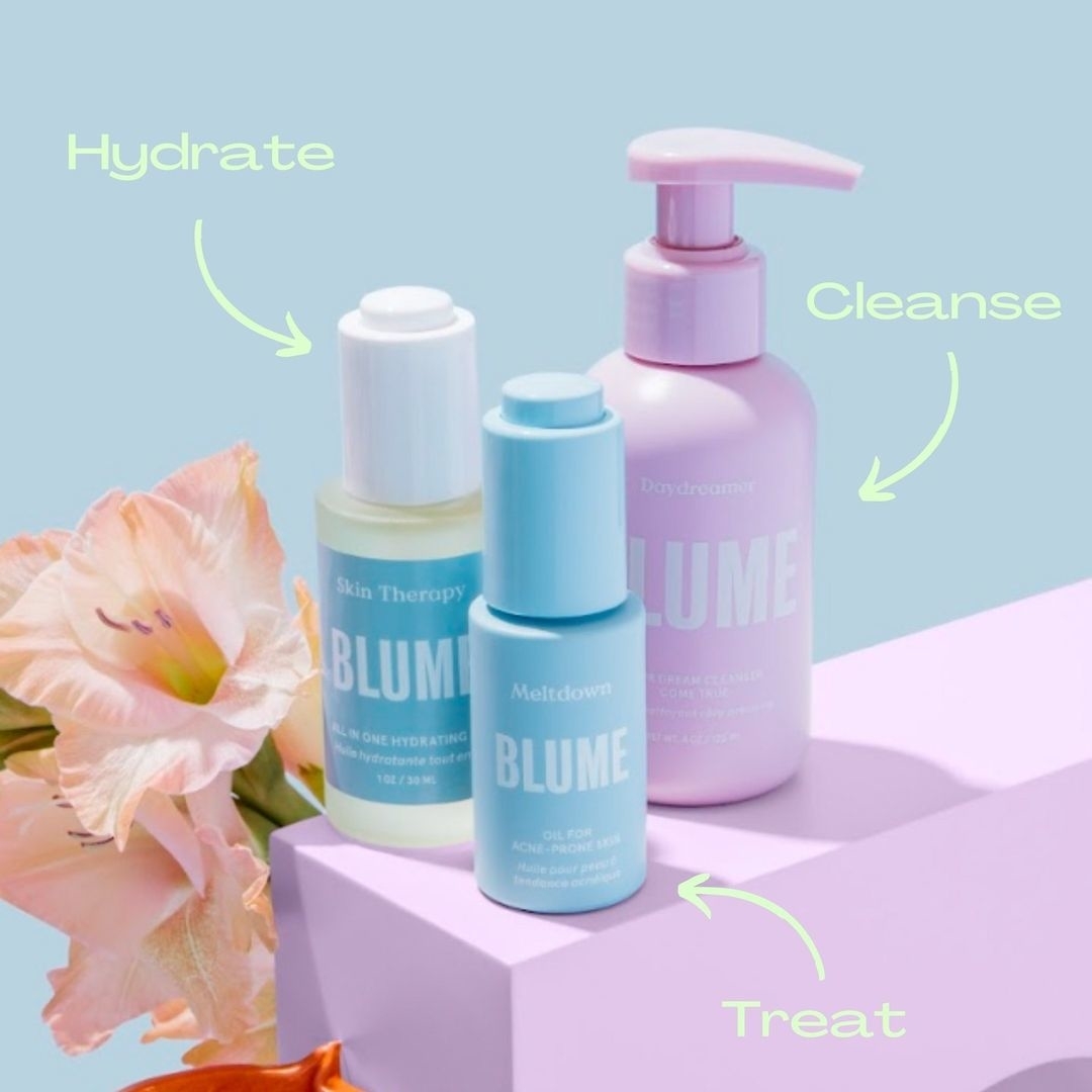 Three bottles of skincare next to a flower