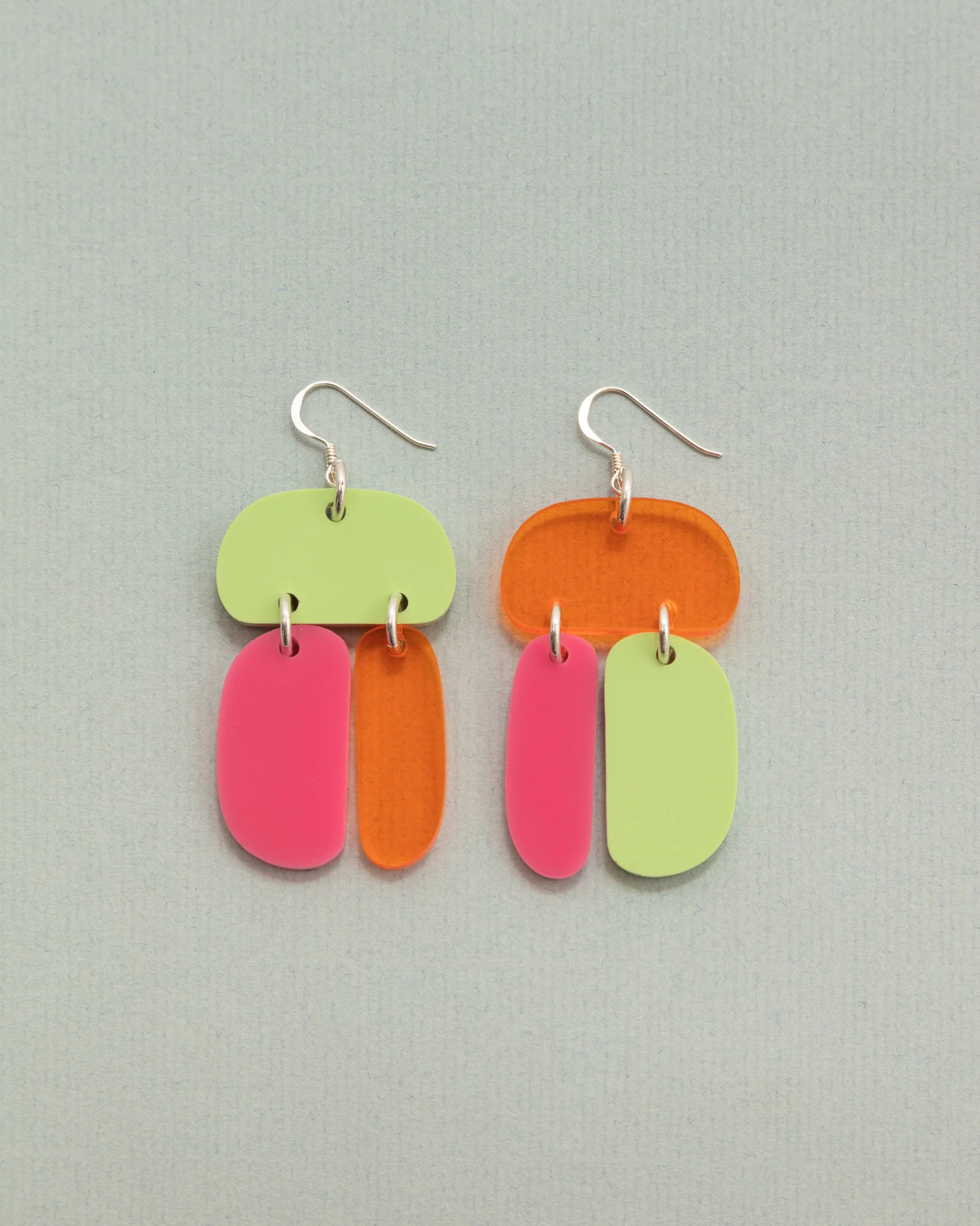 A pair of acrylic earrings on a plain background