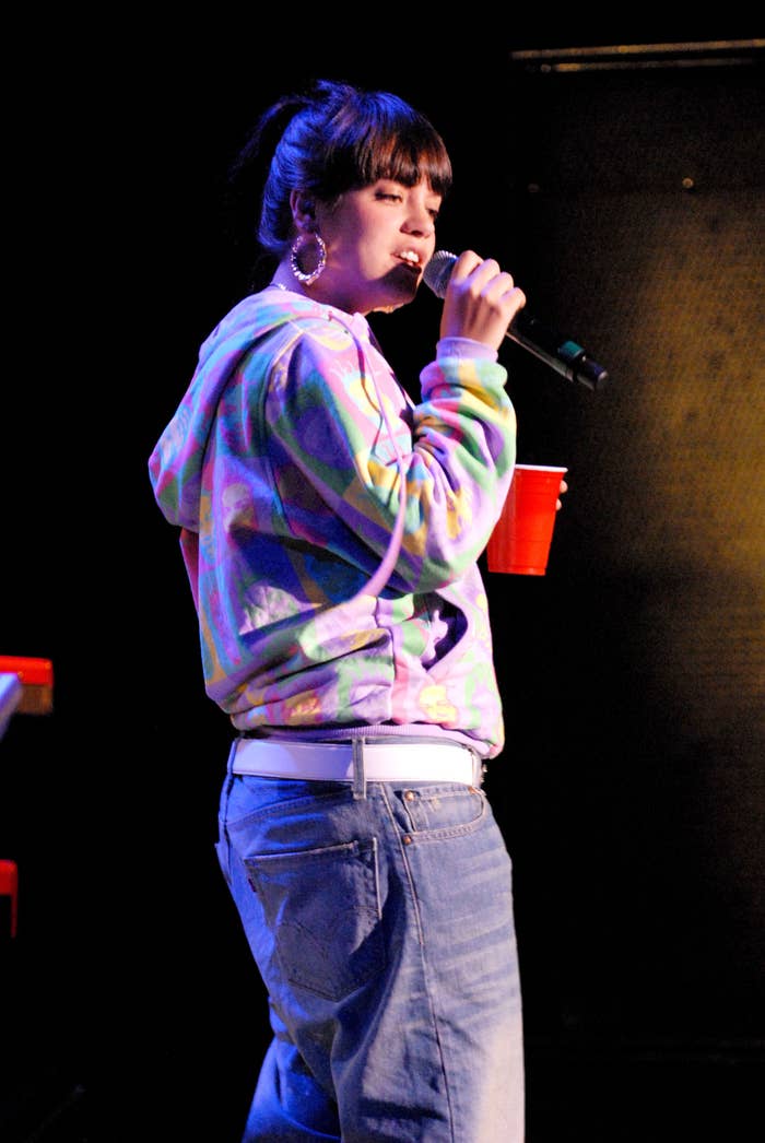 Lily Allen onstage holding a cup