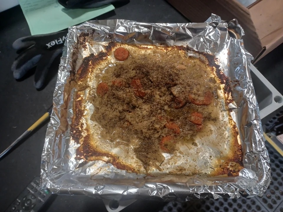 Remnants of soup on a foil-lined baking tray with a burnt ring around it