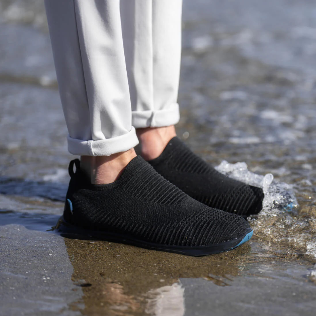 A person wearing slip on sneakers on the beach