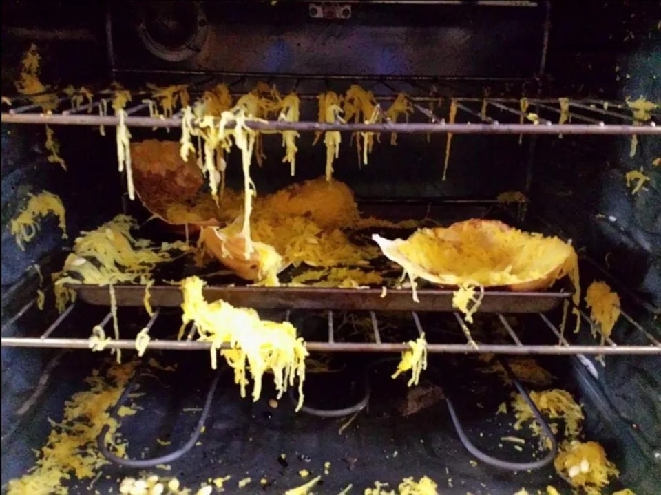 The inside of an oven with strands of spaghetti squash hanging from the racks