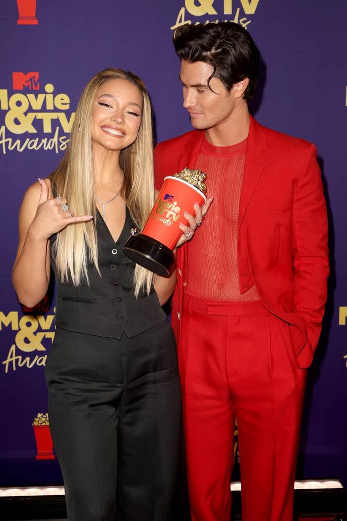 Chase Stokes and Madelyn Cline smiling at a media event