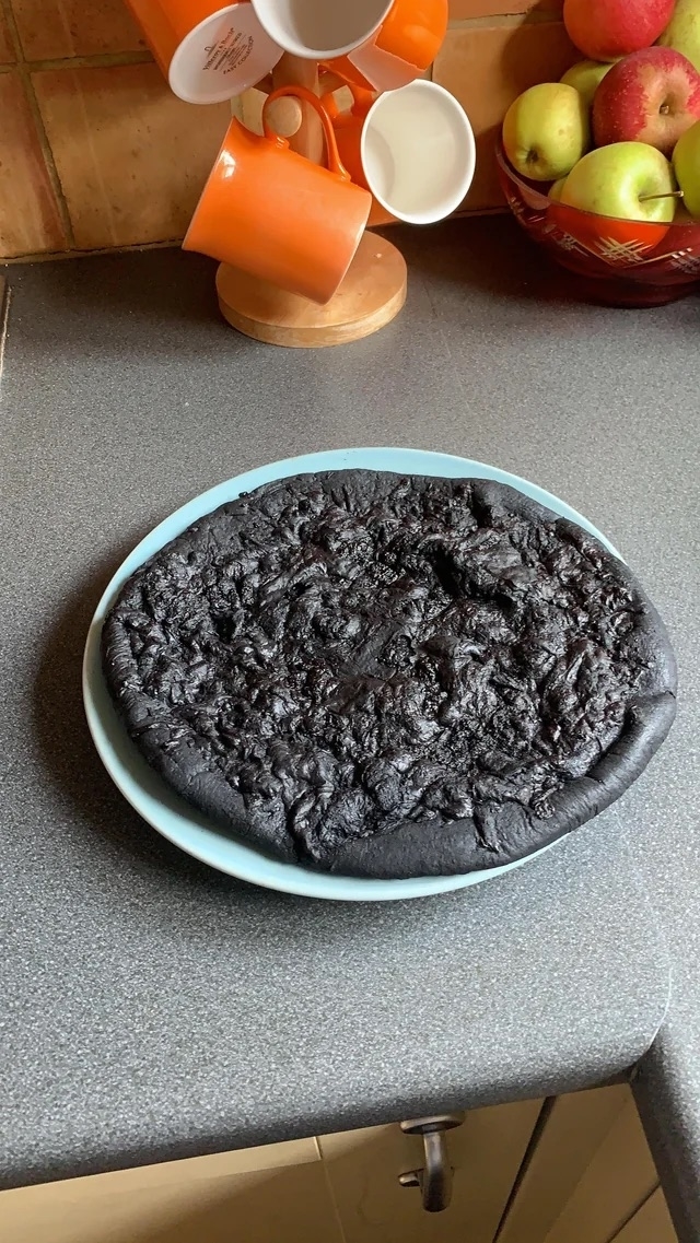 A pizza that is completely black from being charred in the oven