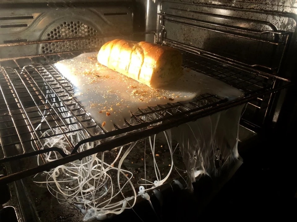 A loaf of bread on top of a melted plastic cutting board in the oven