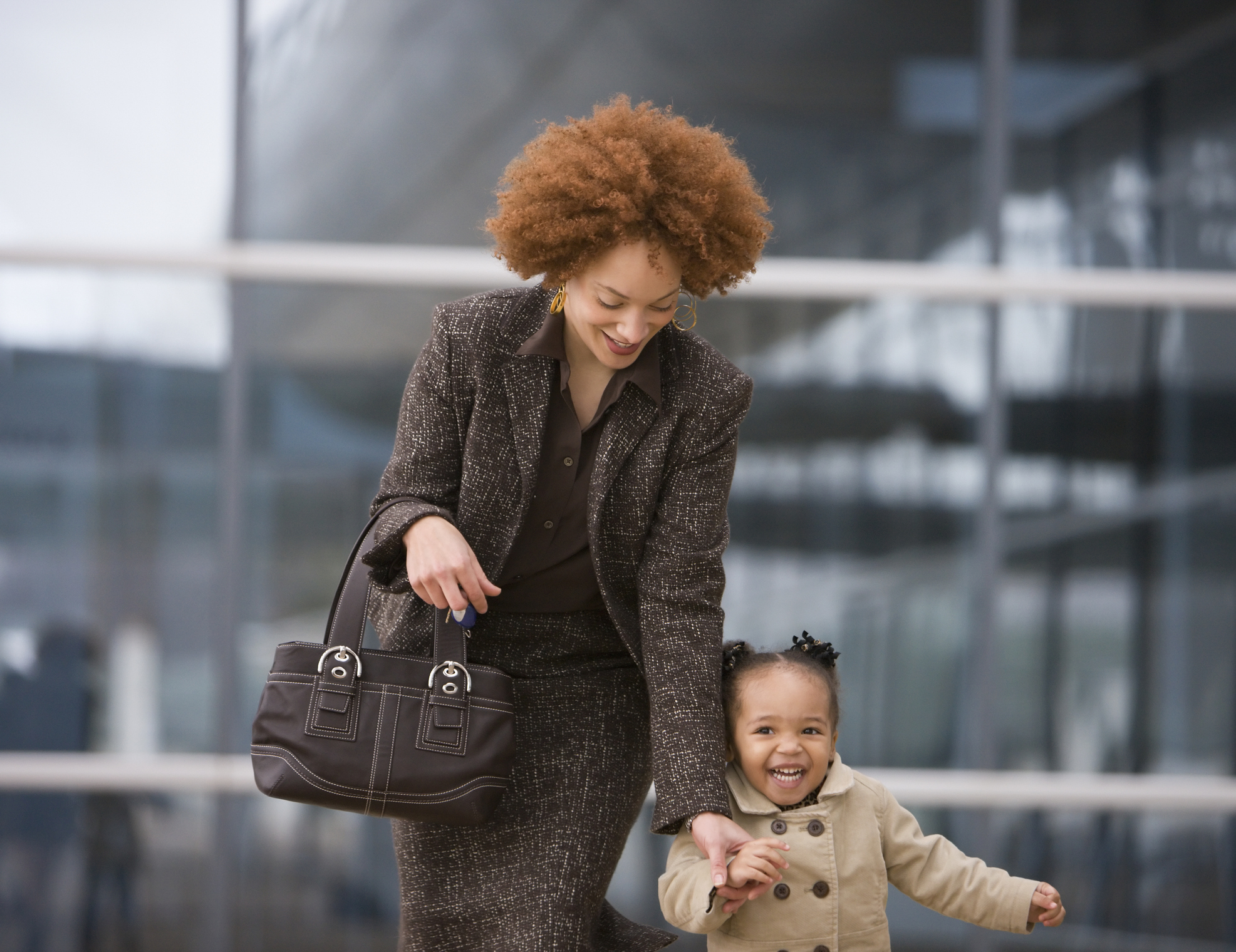 A mother in a suit holding her child&#x27;s hand as they walk