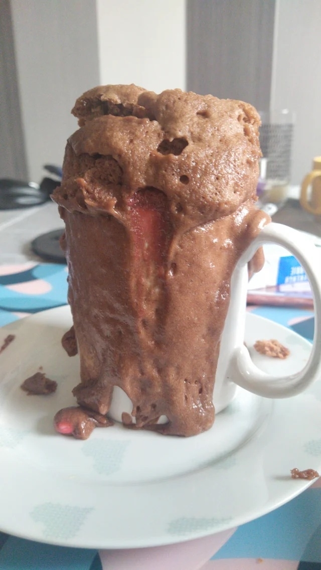 A mug cake that has overflowed and is now spilling over onto the outside of the mug