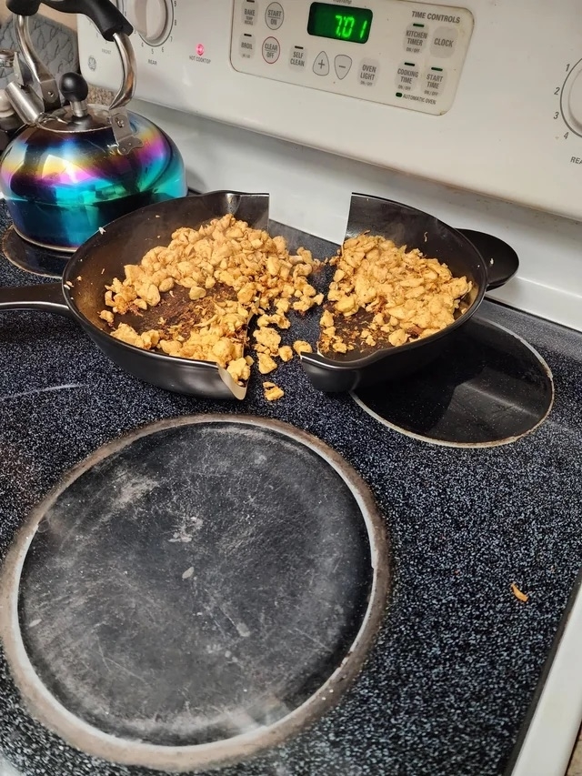 A pan with unknown, burnt contents split in half on a stove