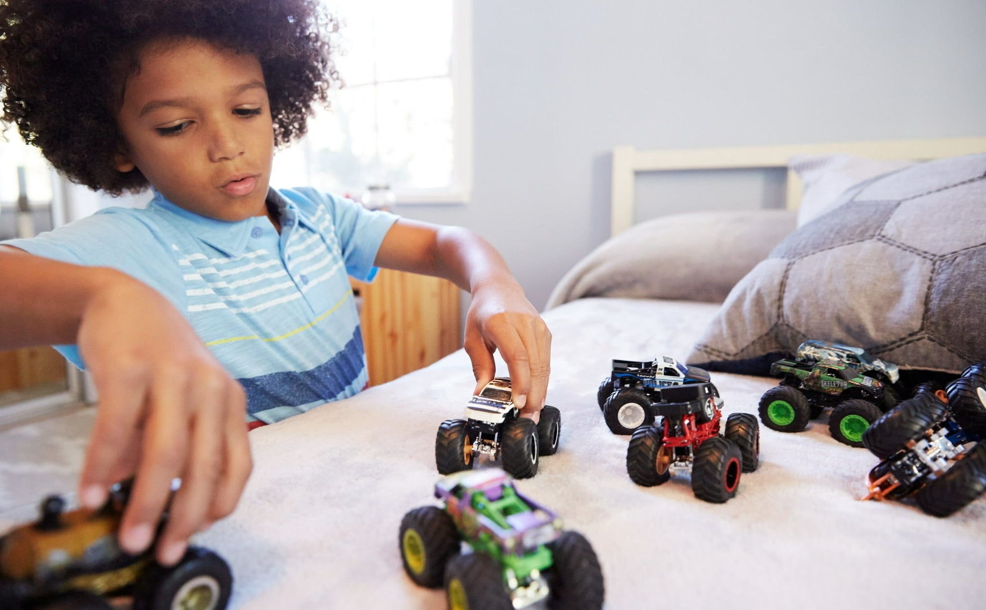 a kid playing with trucks on a bed