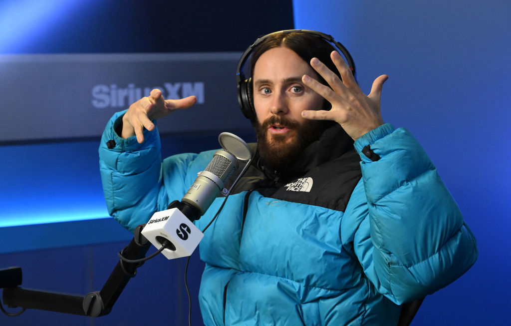Close-up of Jared sitting at a microphone with headphones on and gesturing