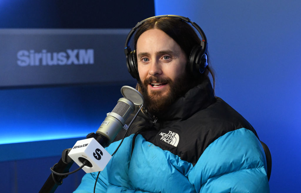 Close-up of Jared sitting at a microphone with headphones on and wearing a puffy jacket