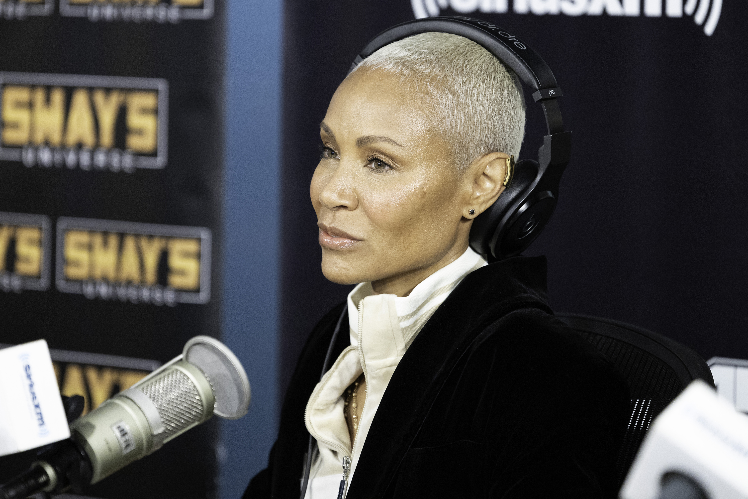 Close-up of Jada sitting in front of a microphone and wearing headphones during an interview