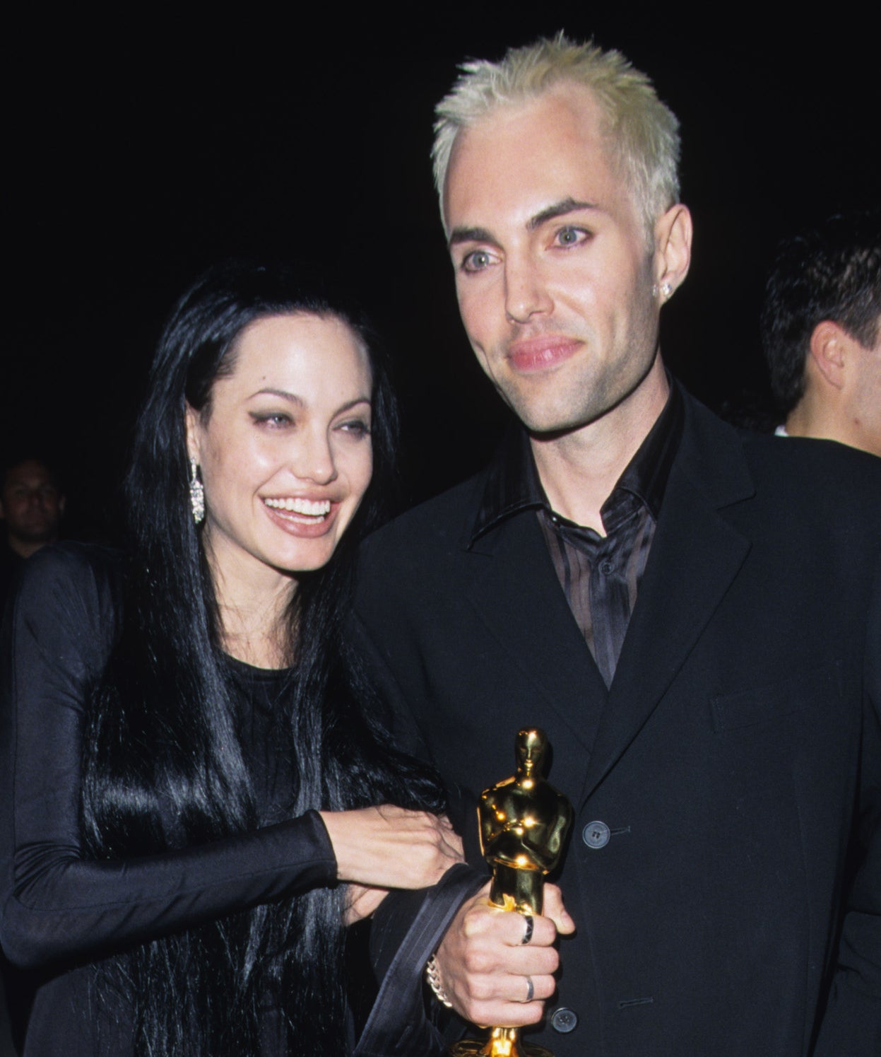 Close-up of Angie and James smiling, with James holding an Oscar