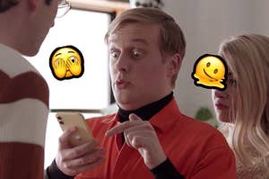 John Early looks at his cell phone, eyes wide and mouth pursed. Surrounding his head is an emoji face with its hands covering its eyes, and on the other side of his head is an emoji face that is melting
