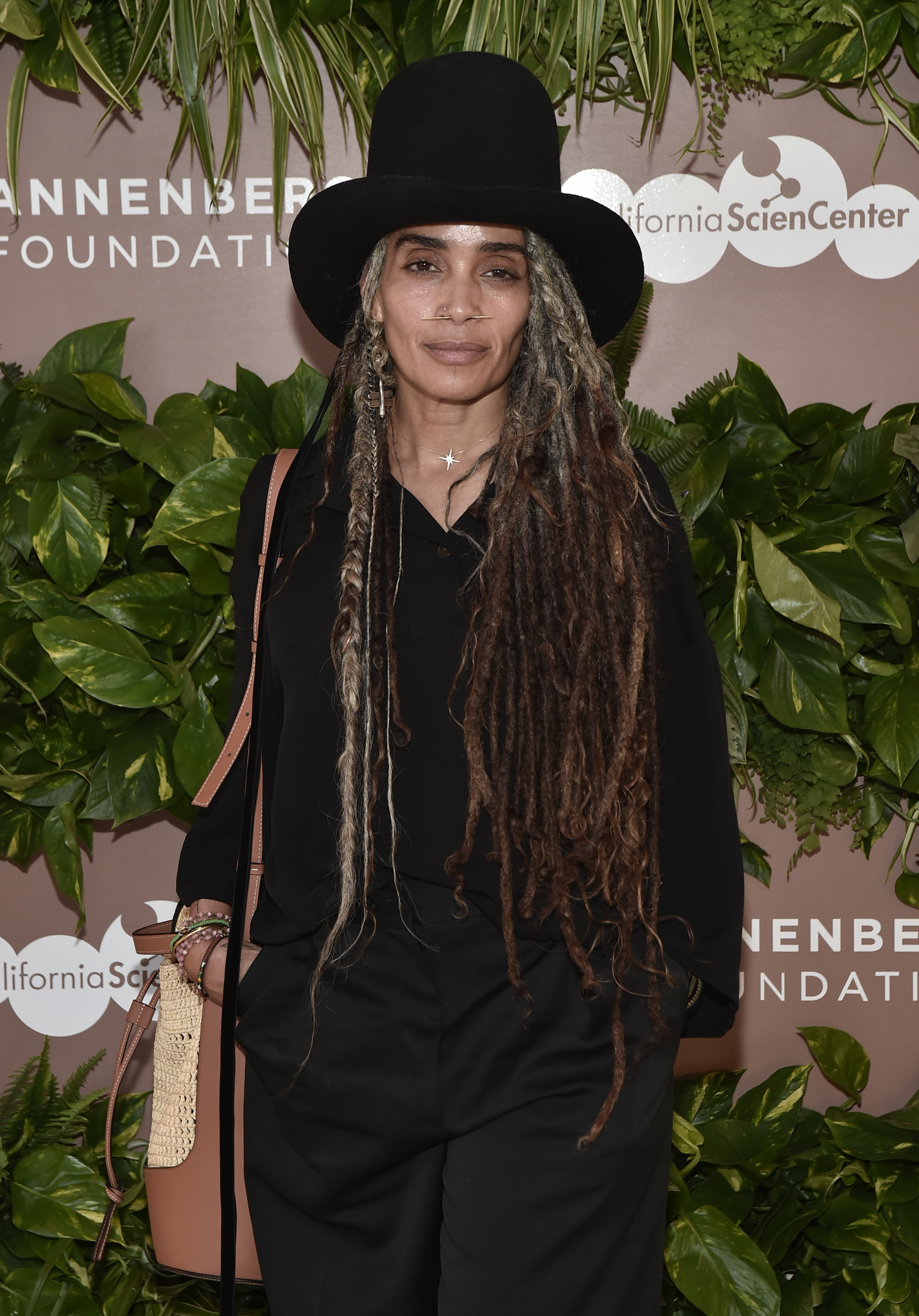 closeup of her at an event with long locs and a tall wide brim hat