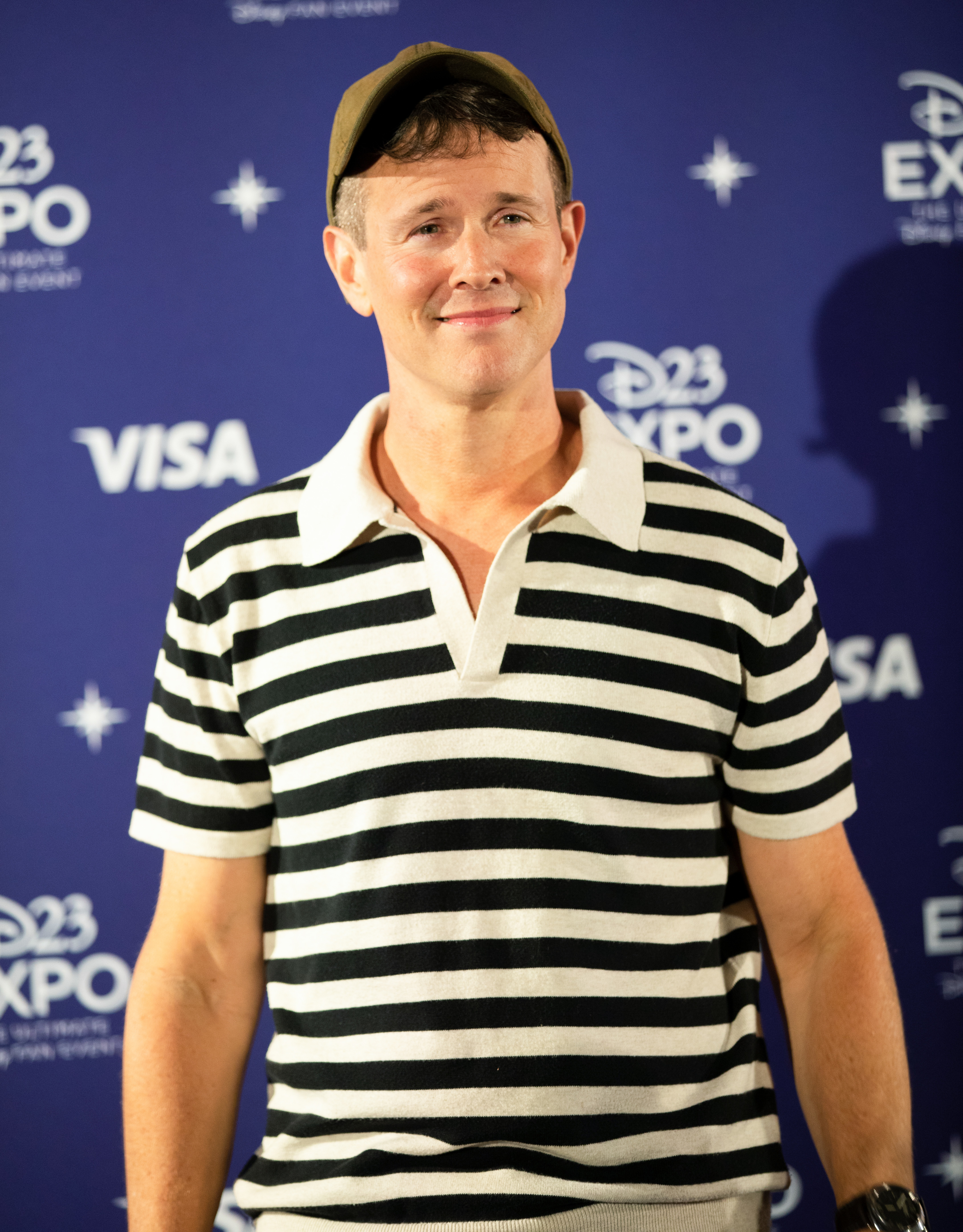 closeup of him in a baseball cap and stripped shirt at an event