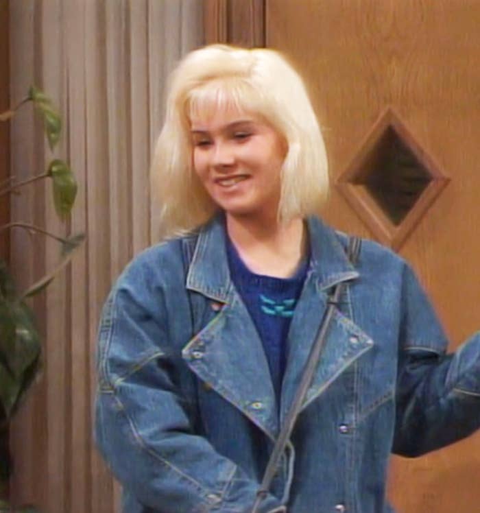 closeup of her character wearing a jean jacket with short blonde hair