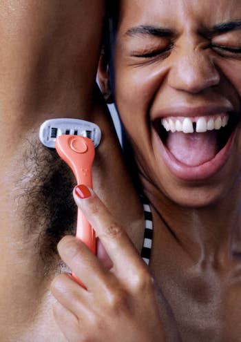model shaving their armpit with a coral-colored razor