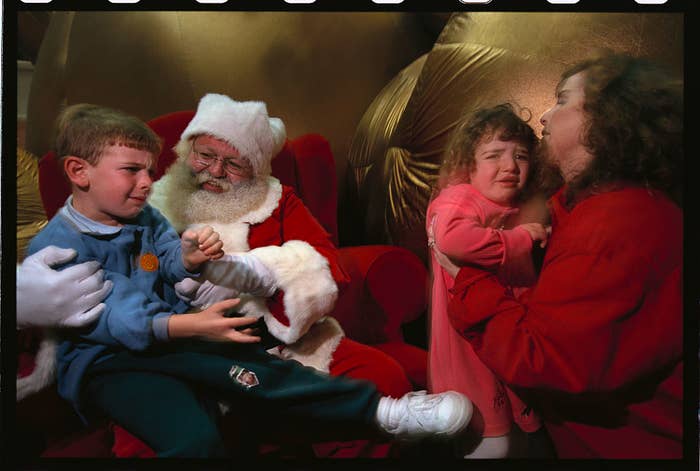 A miserable child in Santa&#x27;s lap, and another waiting for the chance