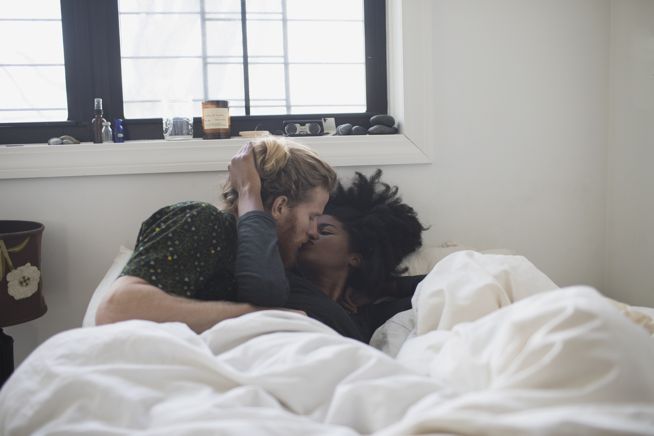 A couple is kissing in bed