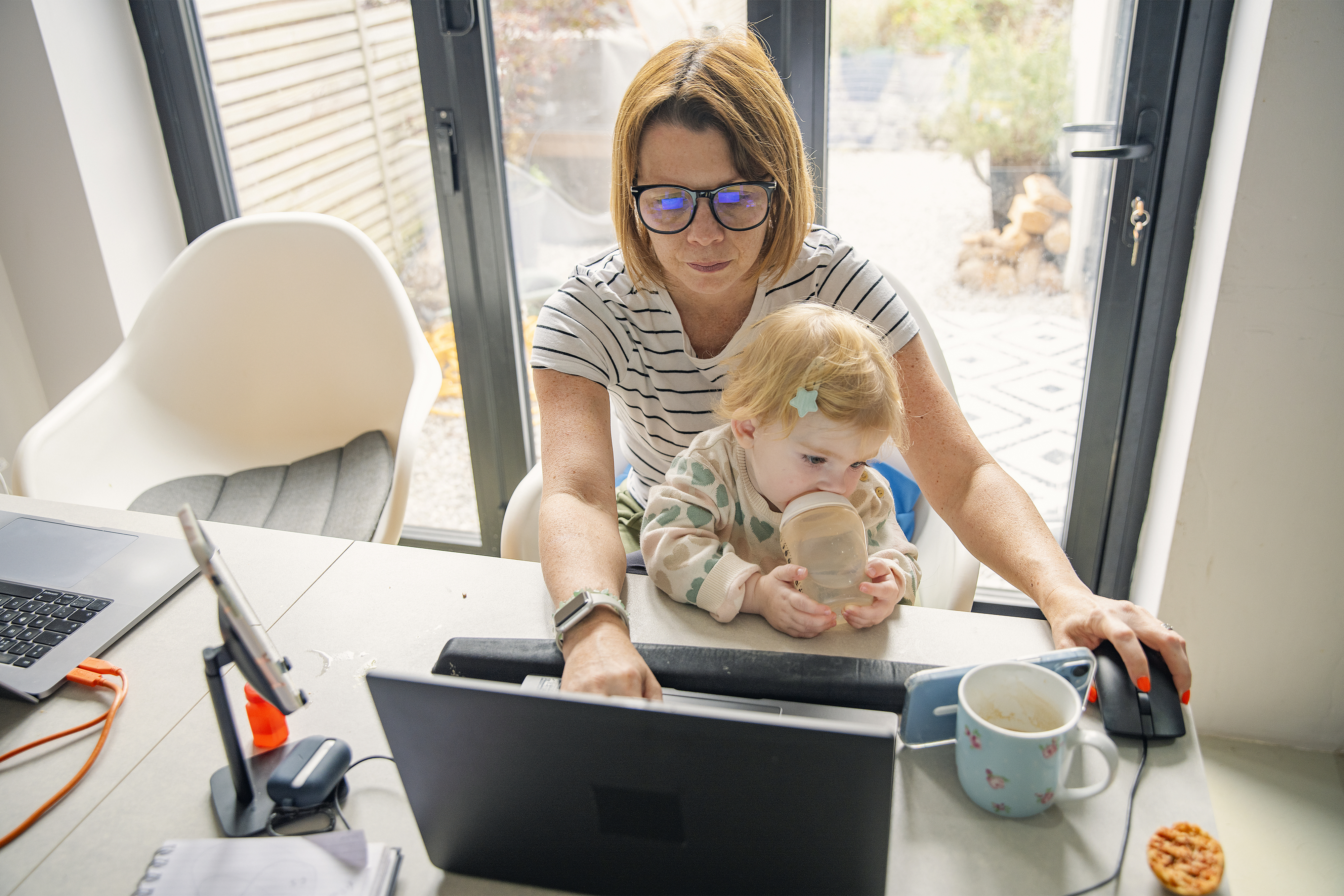 an older woman sitting on the computer with a baby in her lap