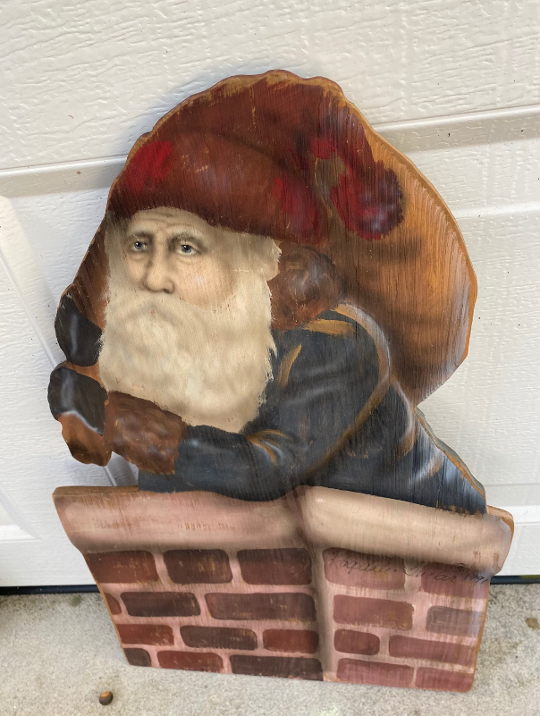 A sad, bearded Santa carrying a sack of gifts and going into a chimney