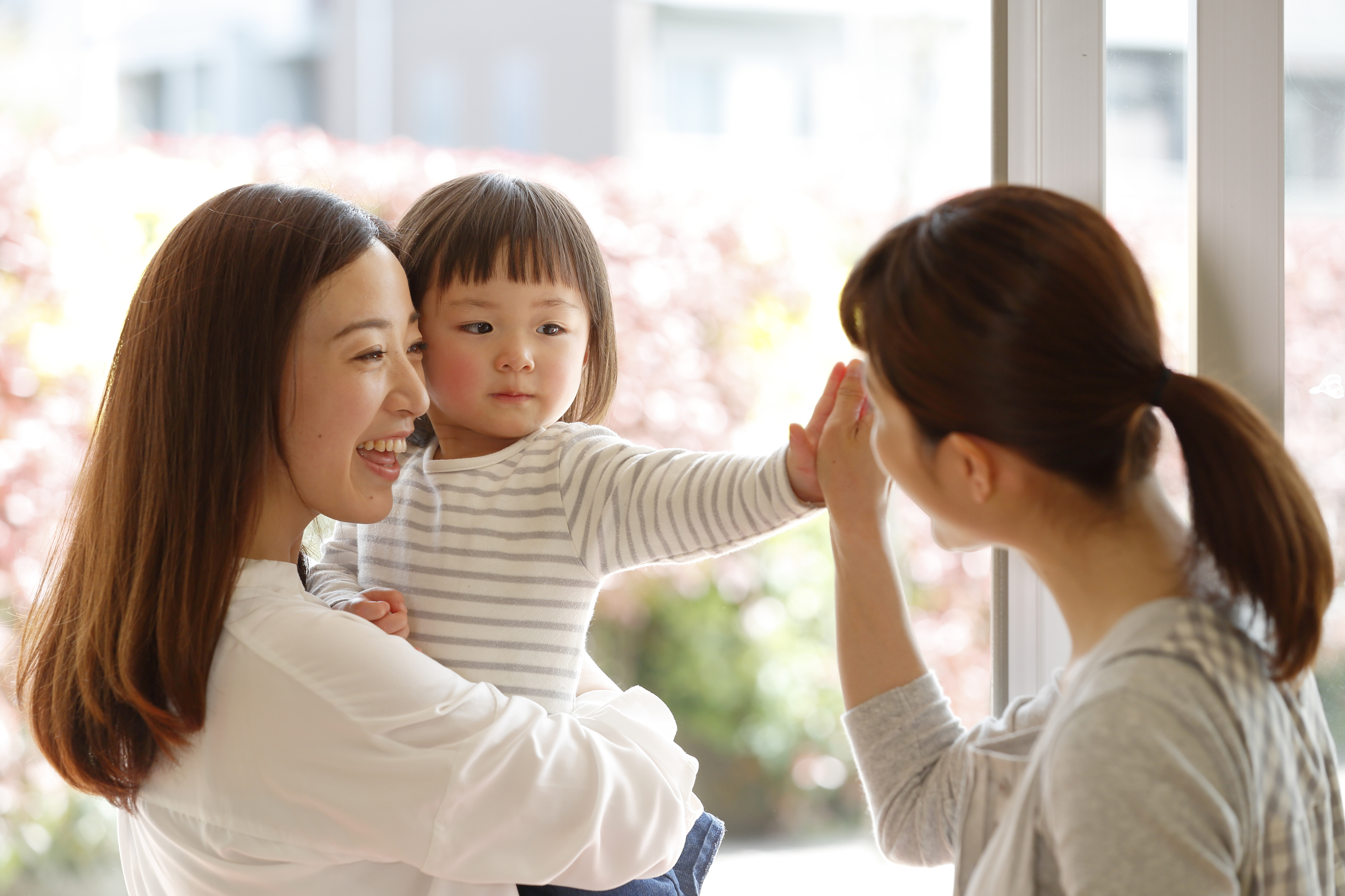 a baby being held by her mom while another woman plays with her