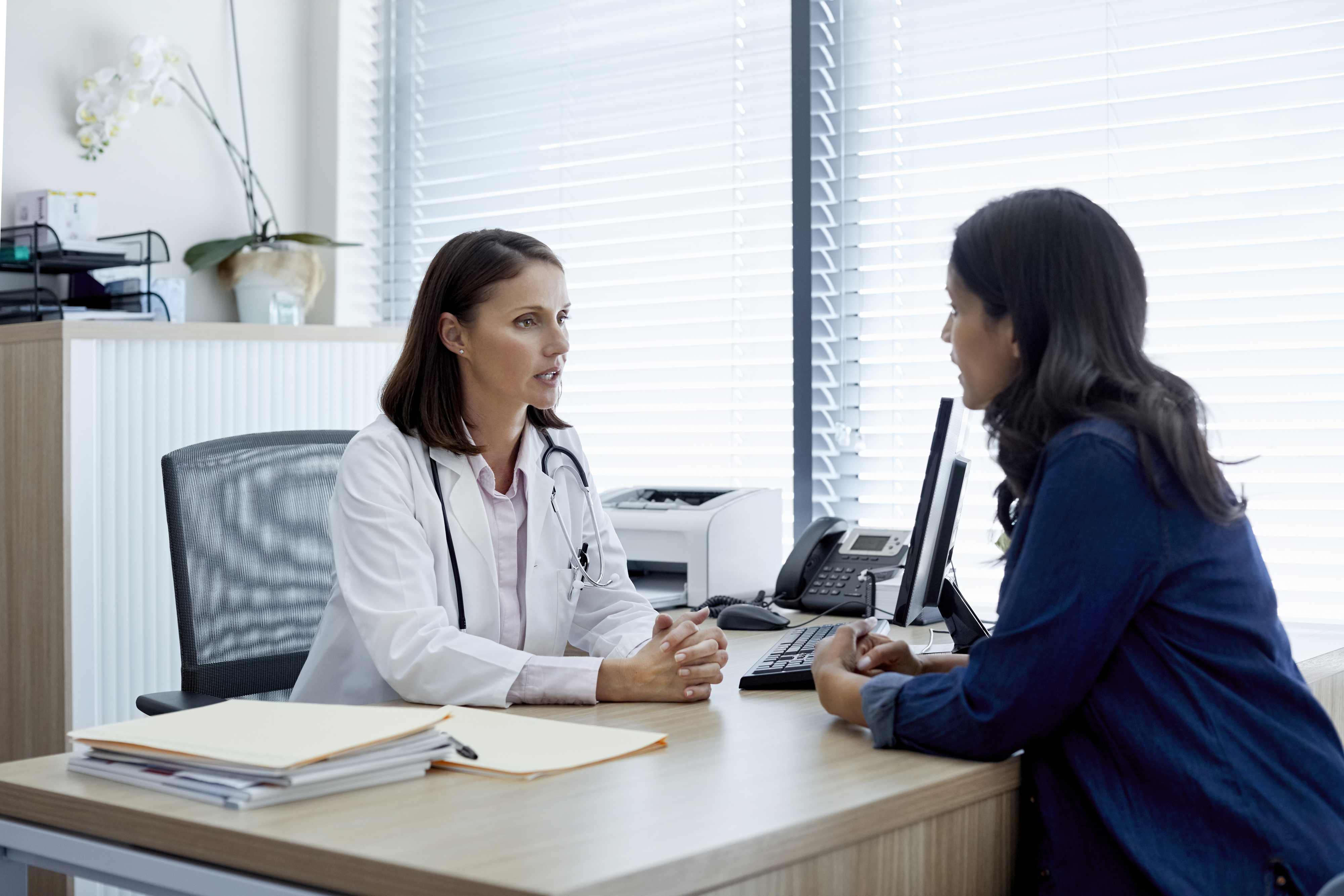 a woman and a doctor sitting at a desk and talking
