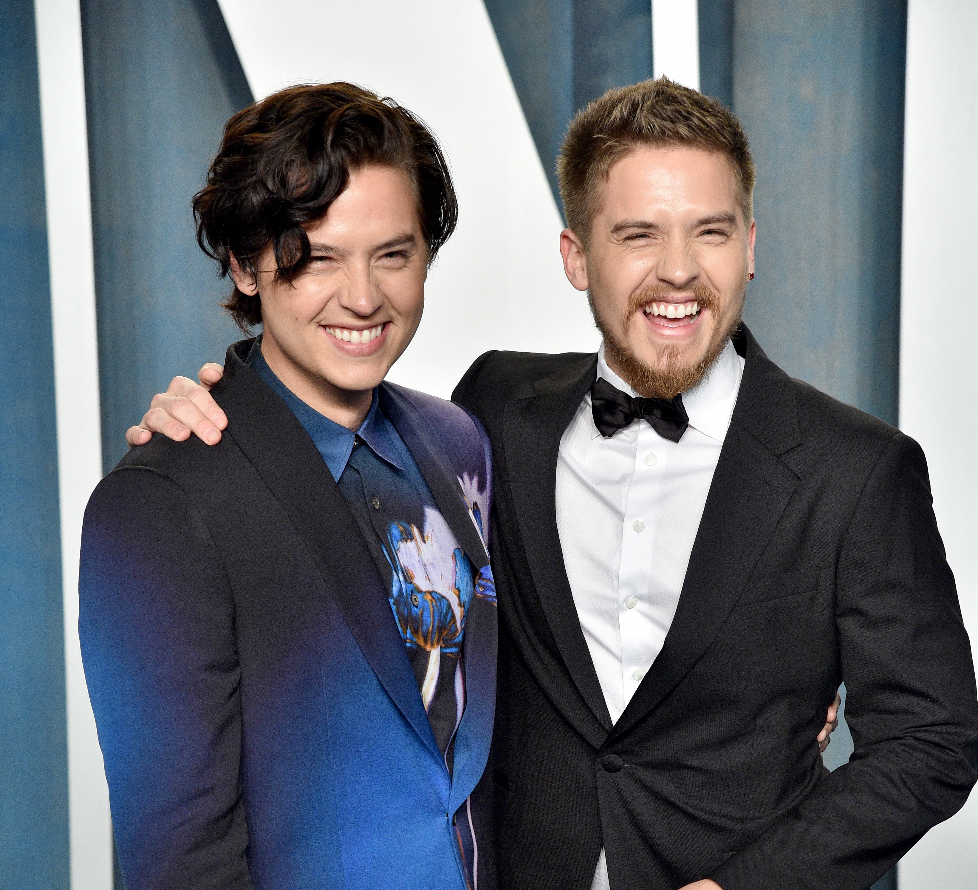 Dylan and Cole as adults smiling at a media event