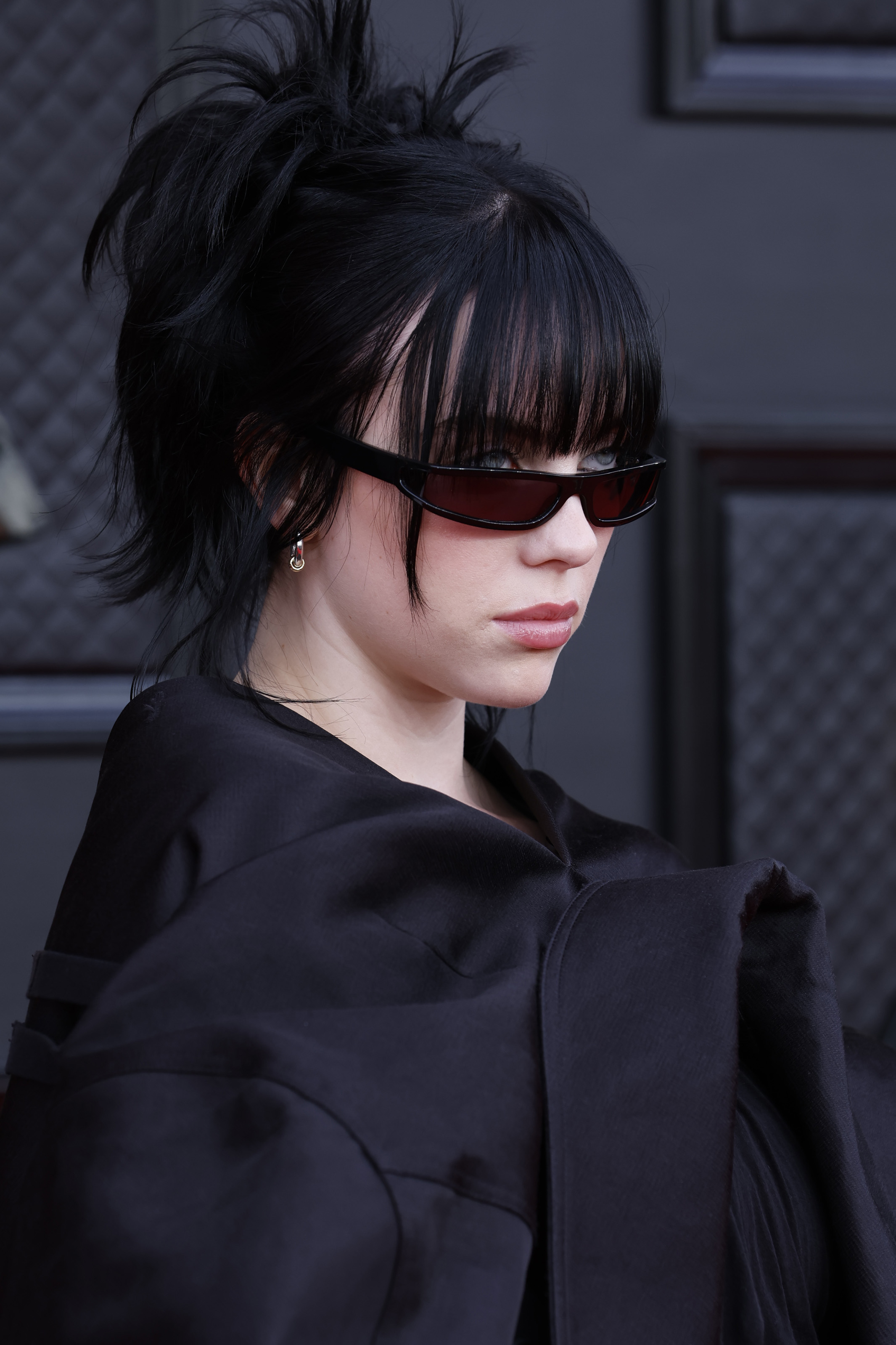 Close-up of Billie with dark hair at a media event and wearing sunglasses