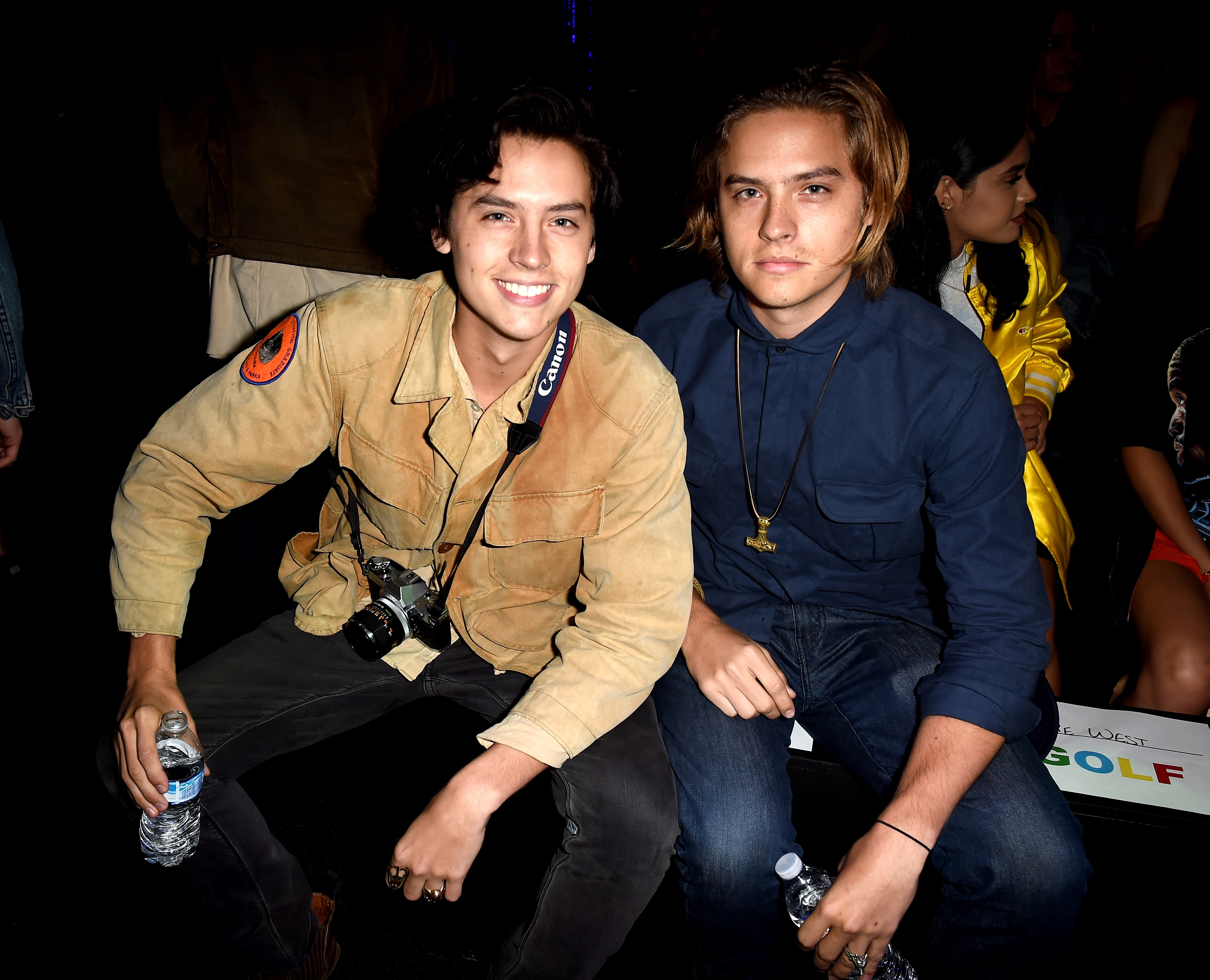 Close-up of Dylan and Cole smiling, sitting together, and holding bottles of water