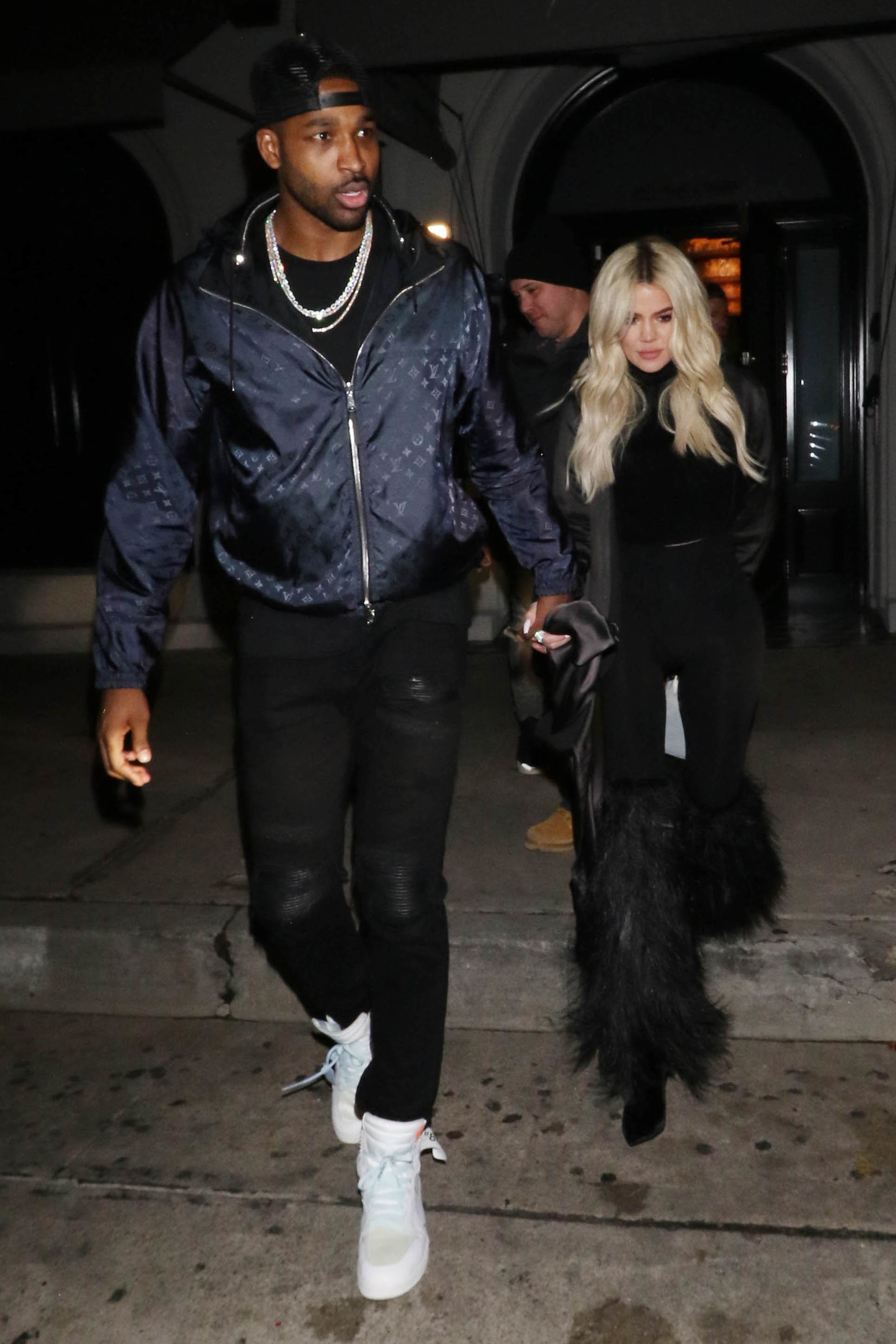 Close-up of Tristan and Khloé holding hands and walking on the street