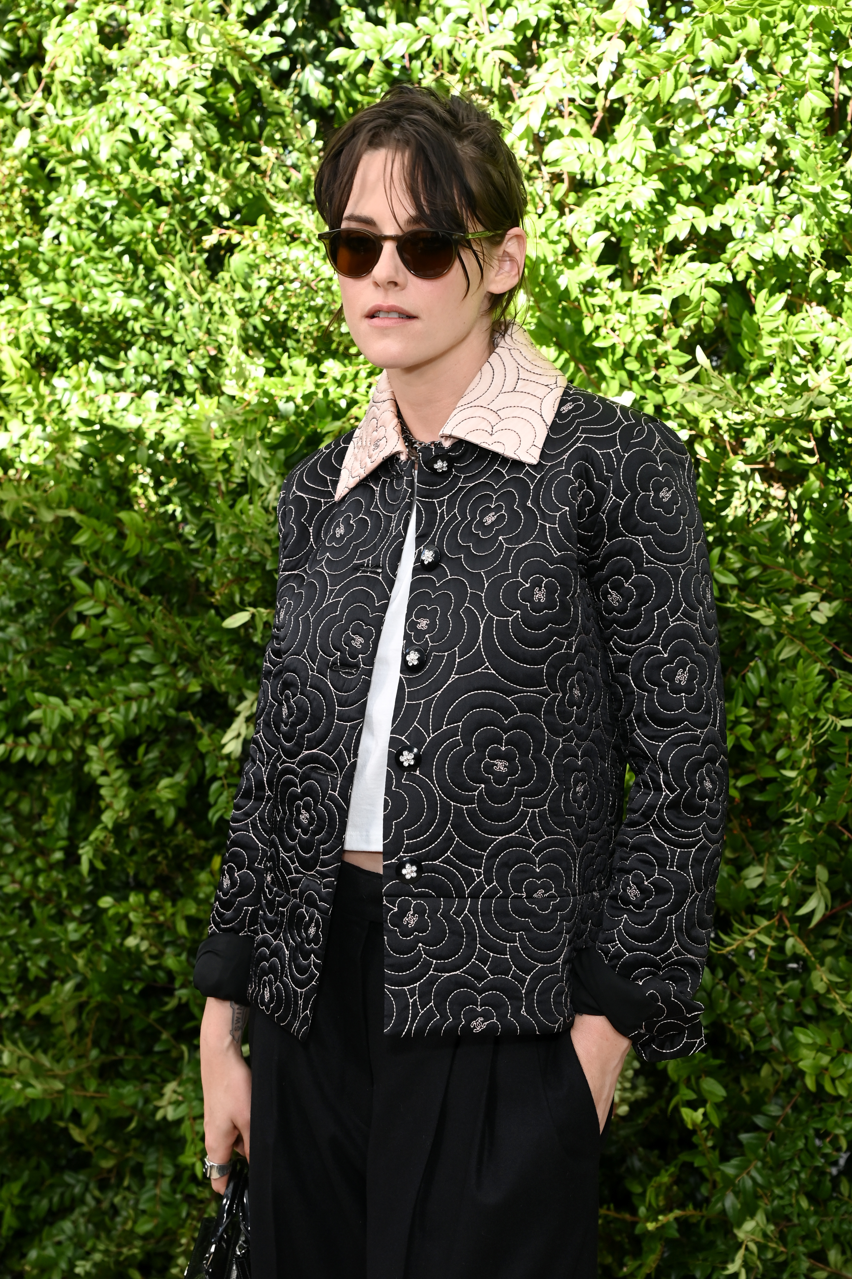 closeup of her wearing an embroidered jacket with short hair and sunglasses