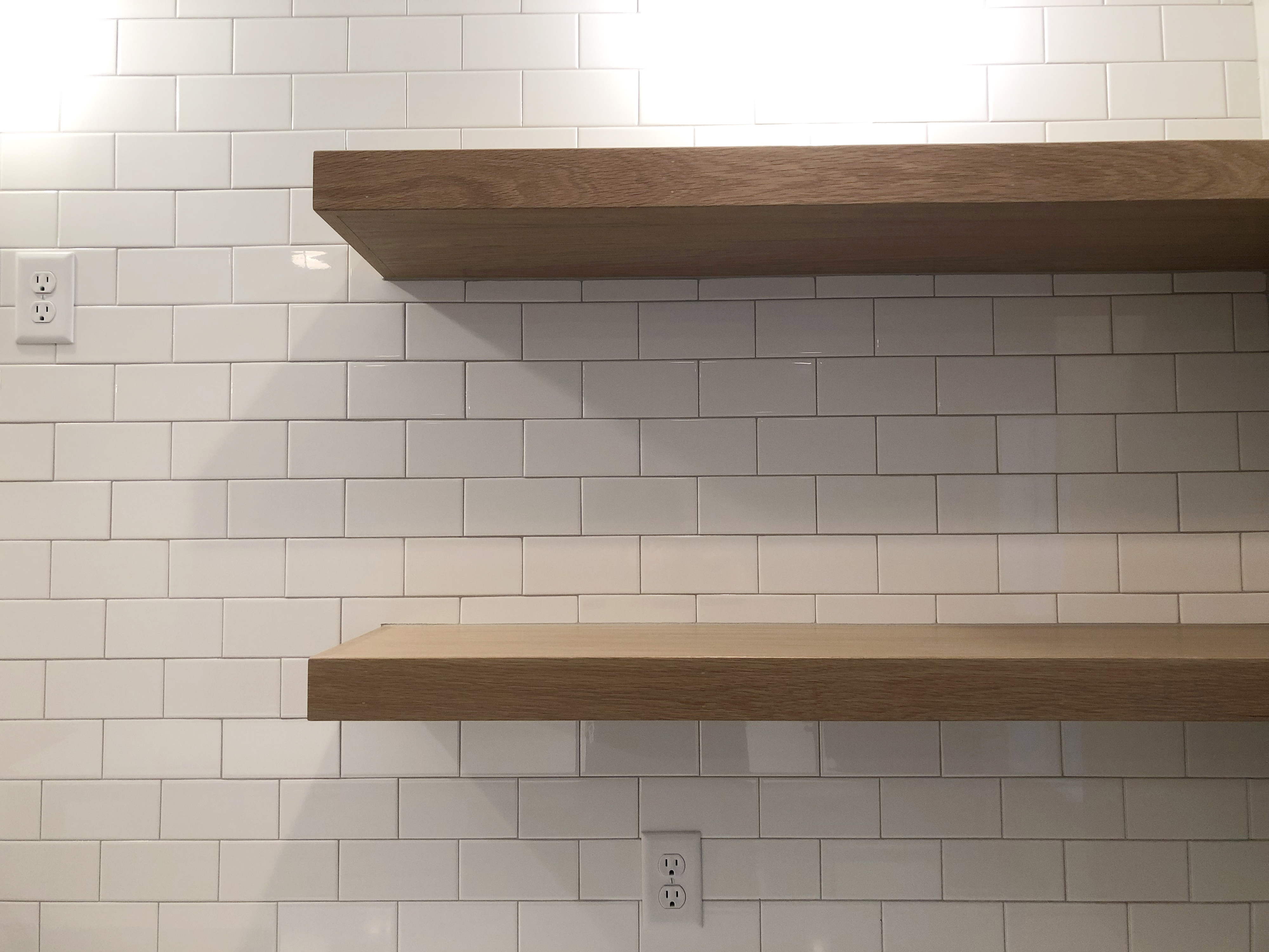 wood shelves against a subway tile wall in a kitchen