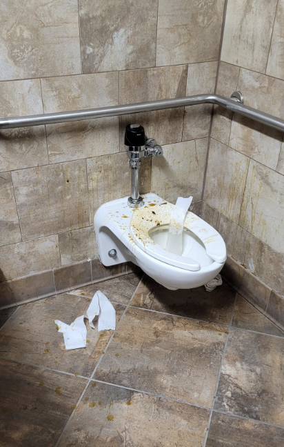a disgusting bathroom with pee and poop all over the toilet and walls