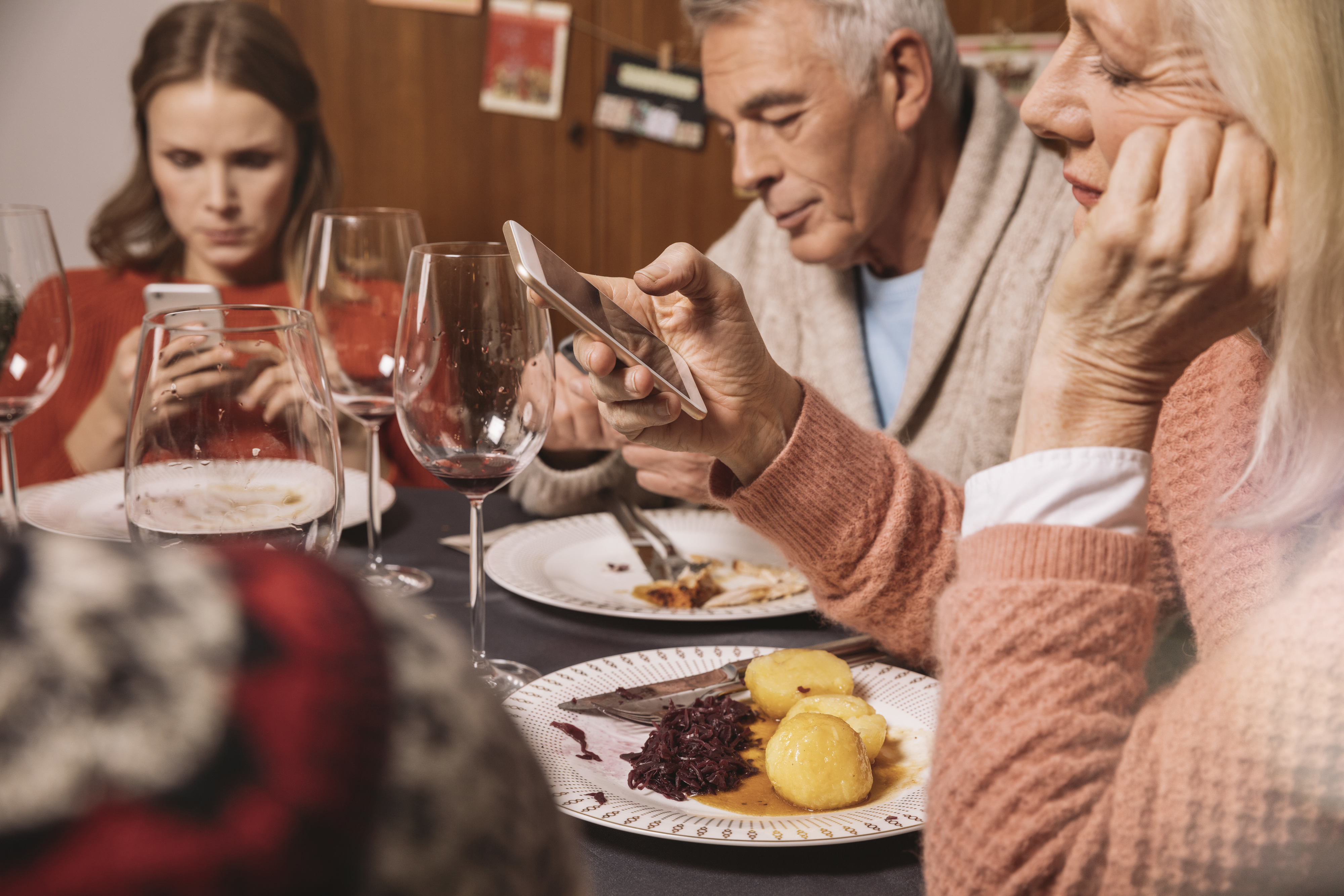 a family sitting at dinner, sitting on their phones and not talking to each other