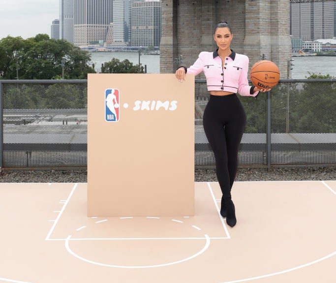 holding a basketball with a poster announcing skims and nba