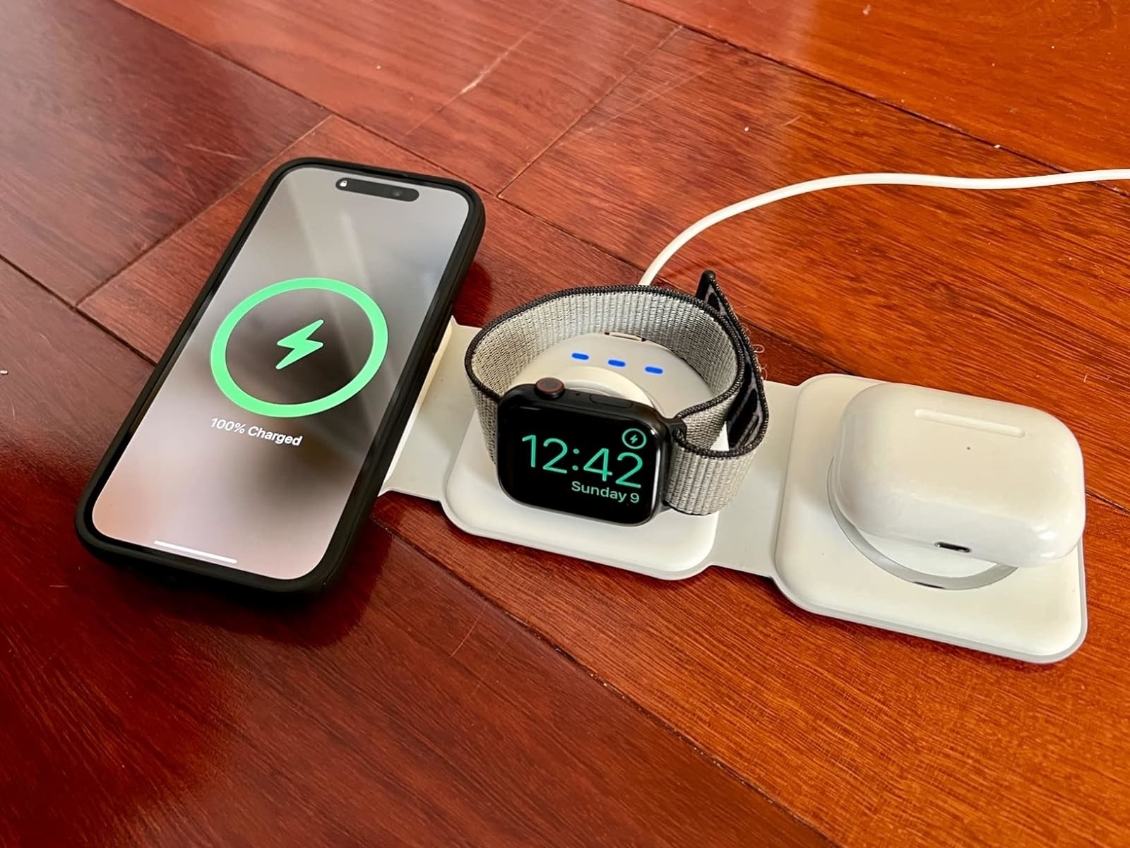 The white charger pad laid out to charge a phone, watch, and AirPods